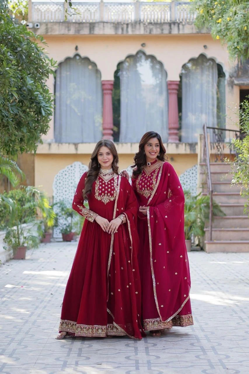 Two women in red traditional outfits standing in front of a building with decorative windows.