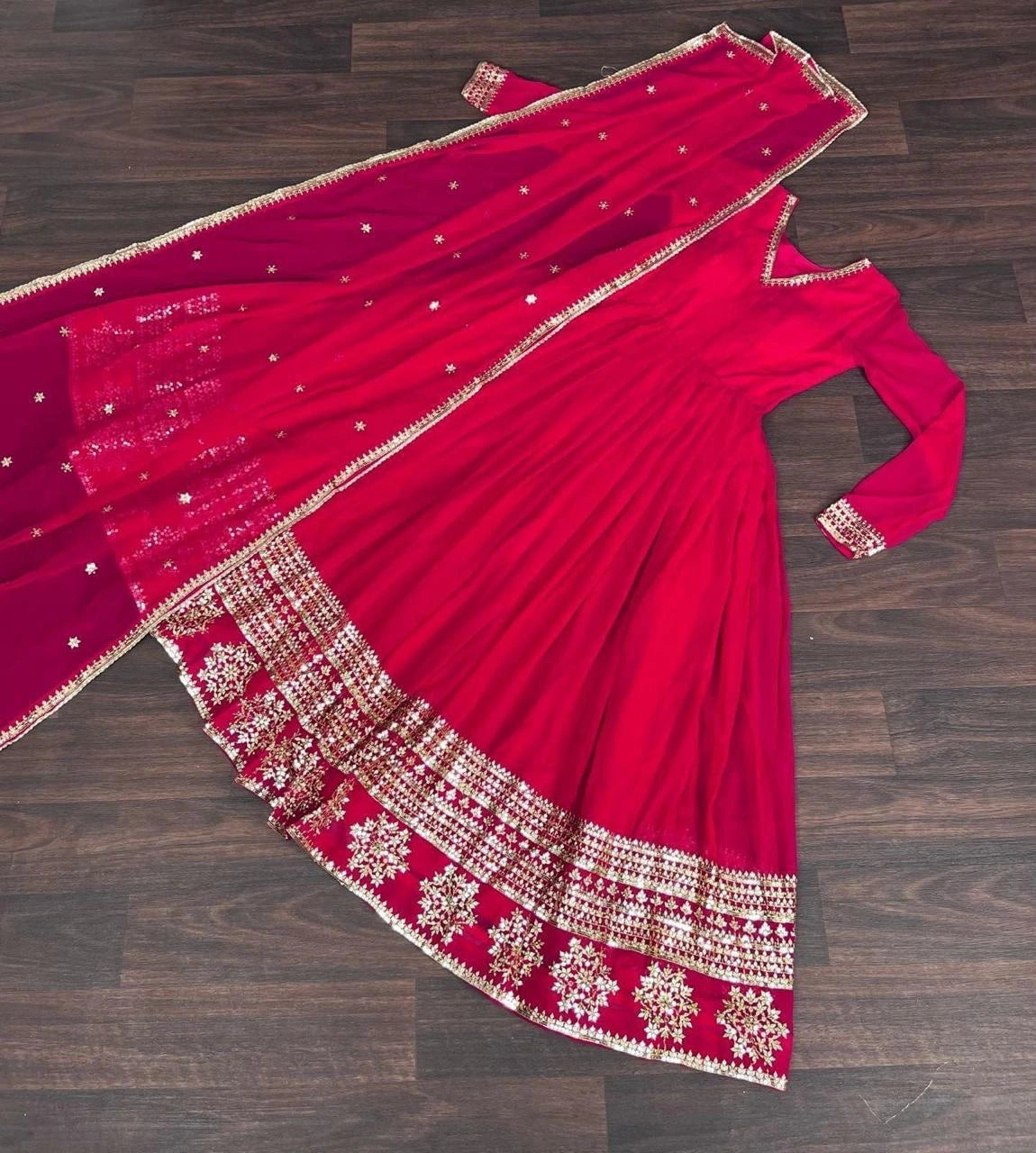 Red saree with gold embroidery on a wooden floor