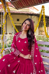 Woman in a red traditional outfit sitting on a swing with floral decorations.