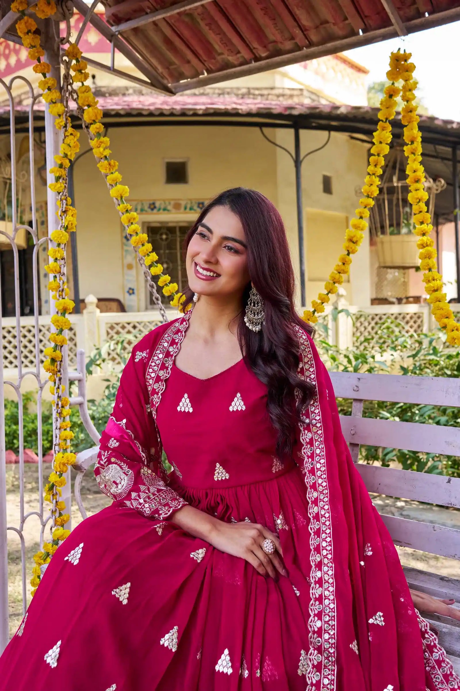 Woman in a red traditional outfit sitting on a decorated swing