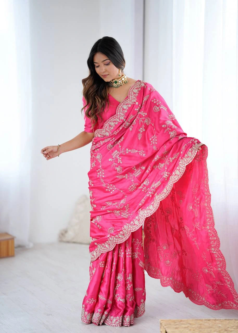 Woman wearing a bright pink saree with gold embroidery in a minimalistic setting