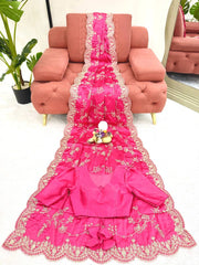 Pink embroidered garment on a pink sofa with a plant and mirror in the background