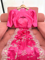 Pink embroidered dress on a hanger against a pink couch.