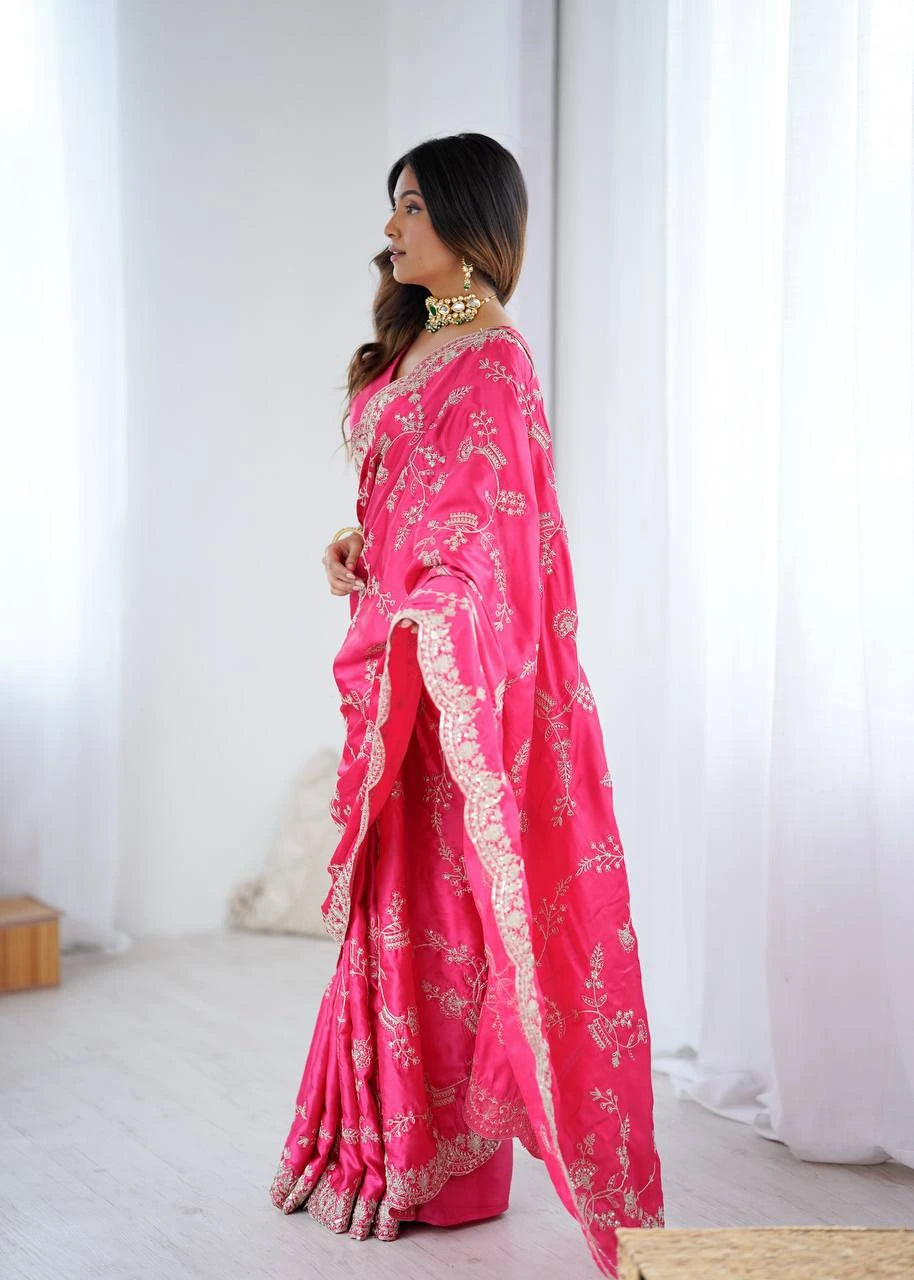 Woman wearing a bright pink saree with white patterns in a minimal indoor setting