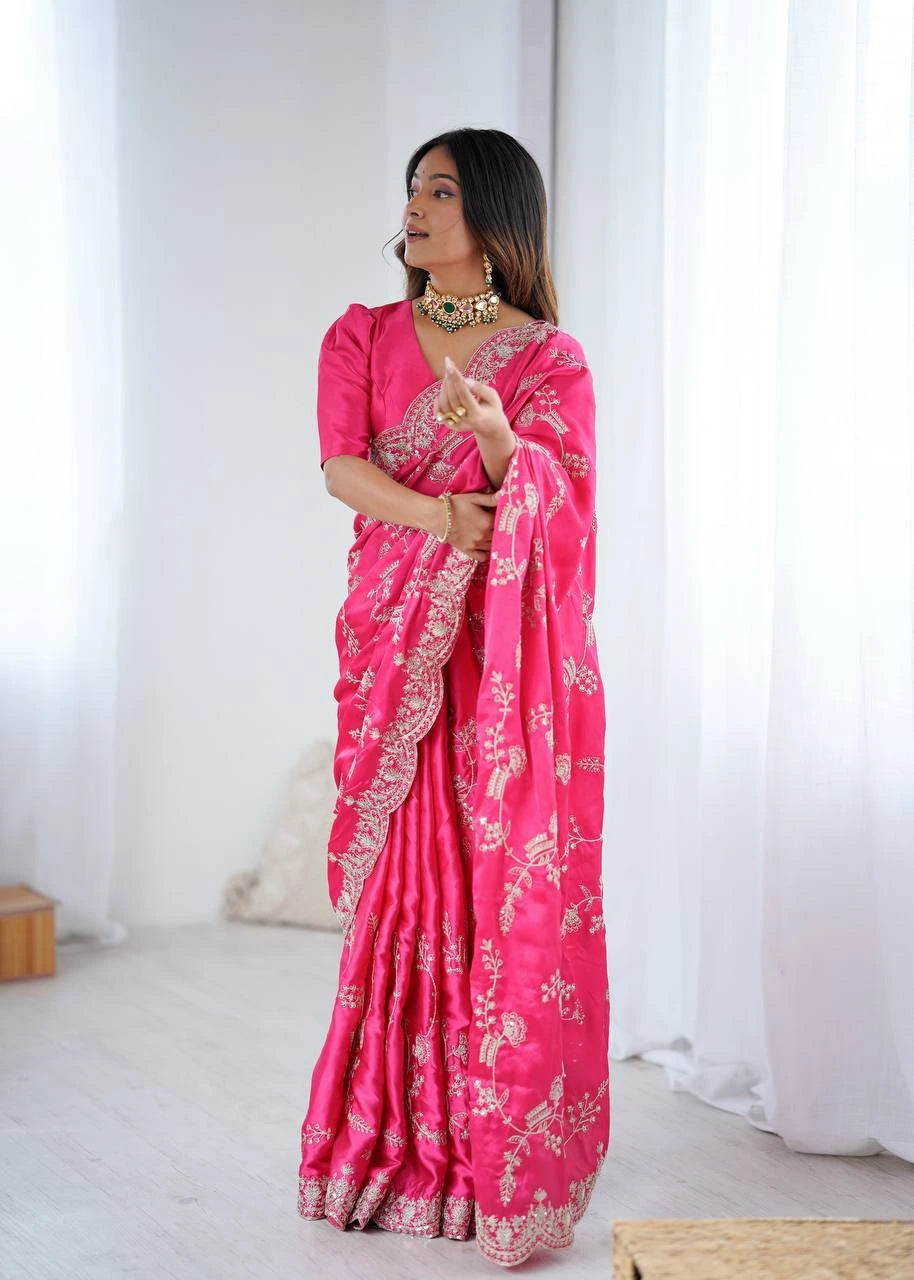Woman wearing a bright pink saree with white patterns in a minimalistic setting