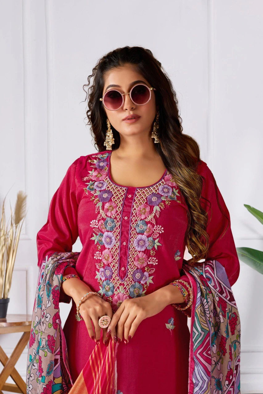 Woman wearing a pink embroidered outfit with a colorful scarf against a white background