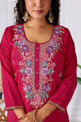 Woman wearing a pink embroidered traditional outfit with a white background