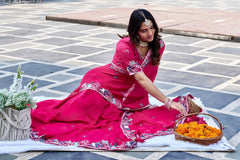 Woman in a pink traditional outfit arranging flowers on a stone pavement.