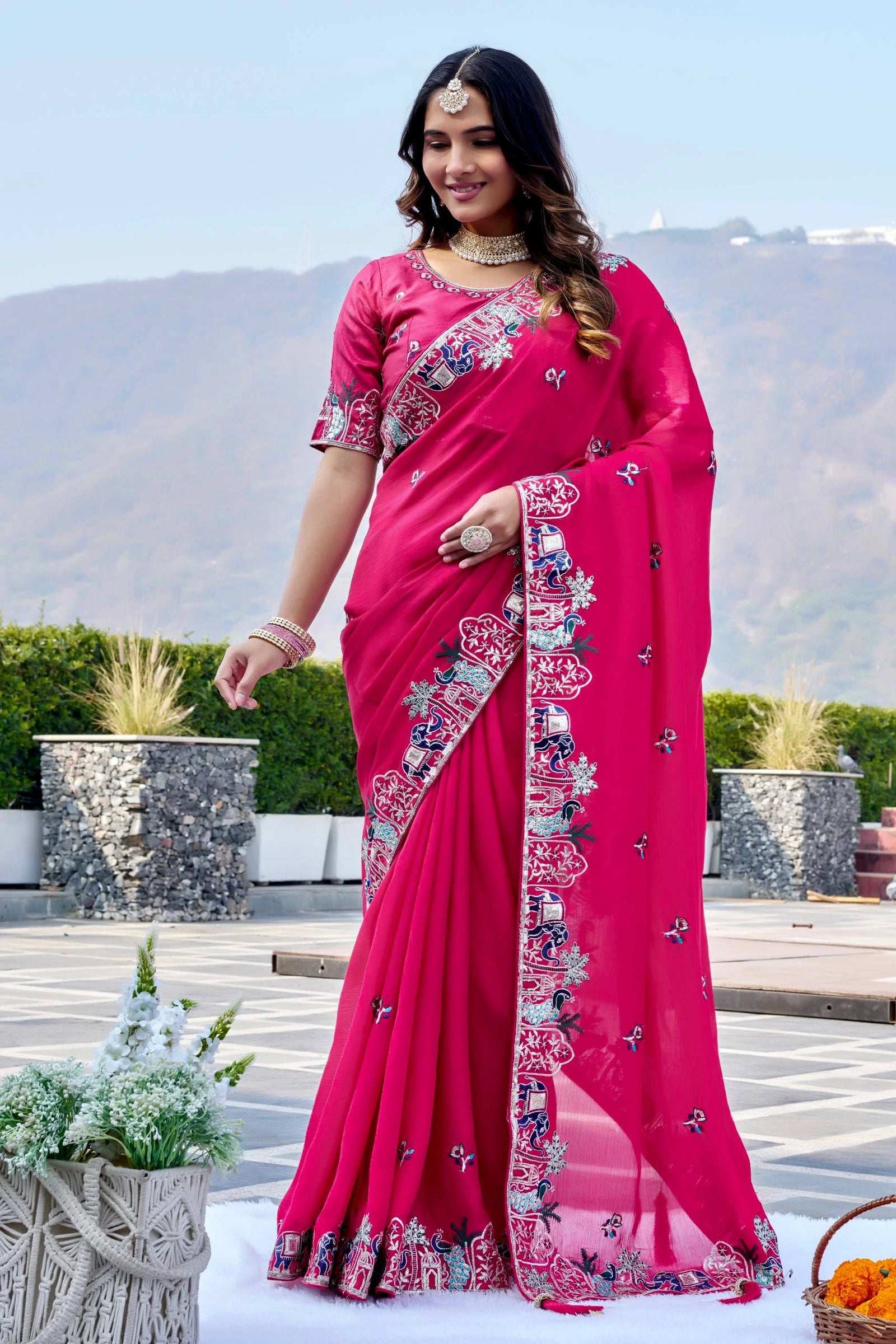 Woman wearing a pink saree with floral patterns outdoors