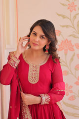 Woman wearing a red traditional outfit with gold embroidery against a floral wallpaper background
