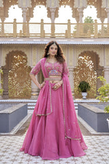 Woman in a pink traditional outfit standing in front of an ornate architectural background