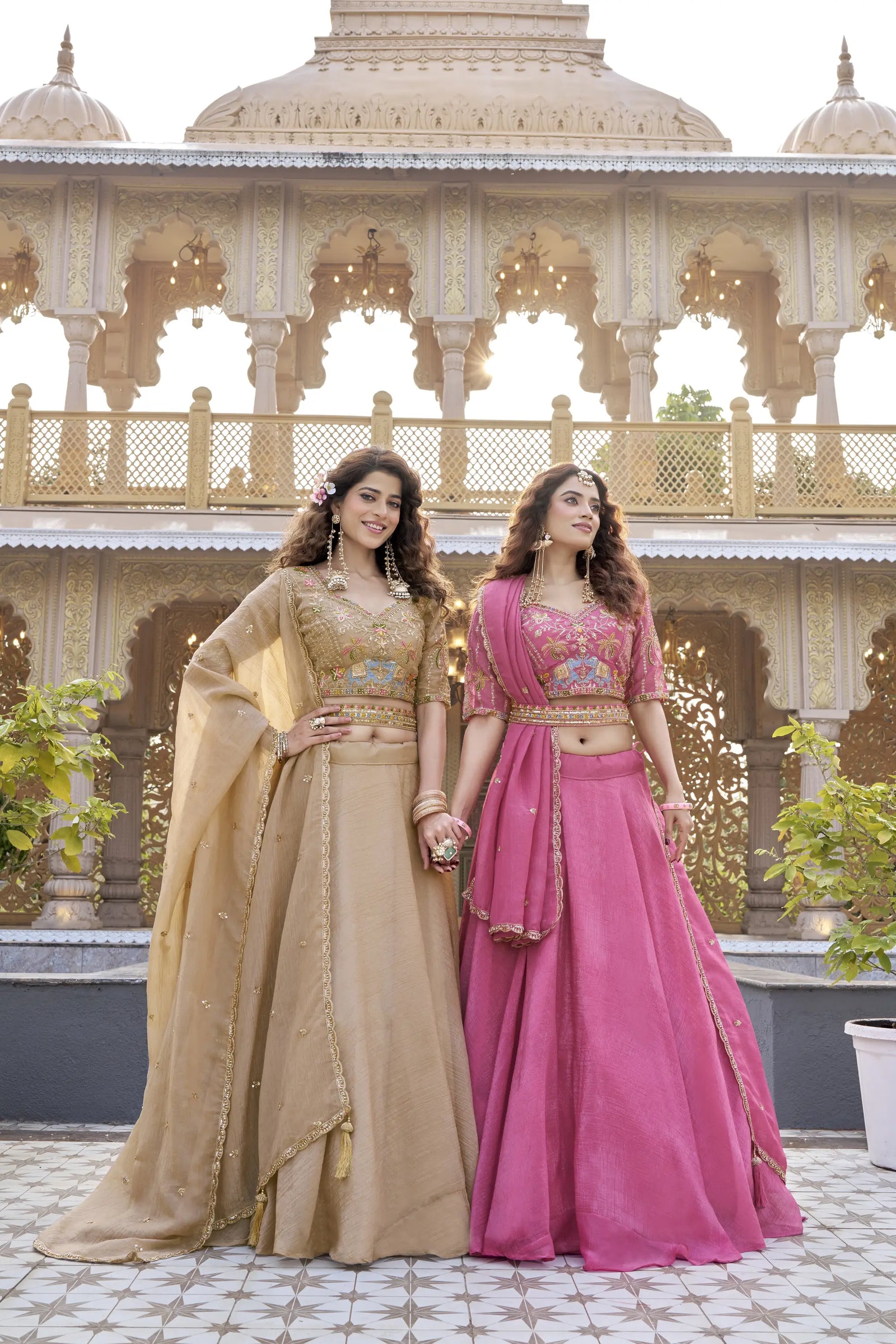 Two women in traditional outfits standing in front of an architectural structure.