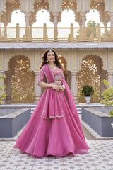 Woman in a pink traditional outfit standing in front of an ornate architectural background