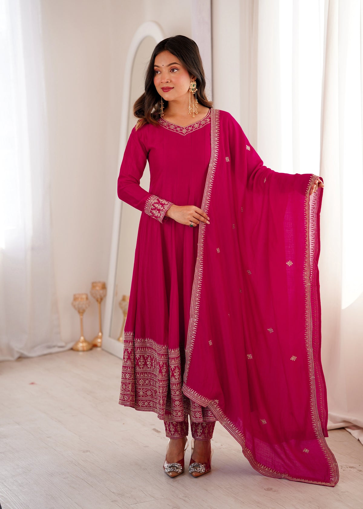 Woman wearing a pink traditional outfit with a matching dupatta in a well-lit room.