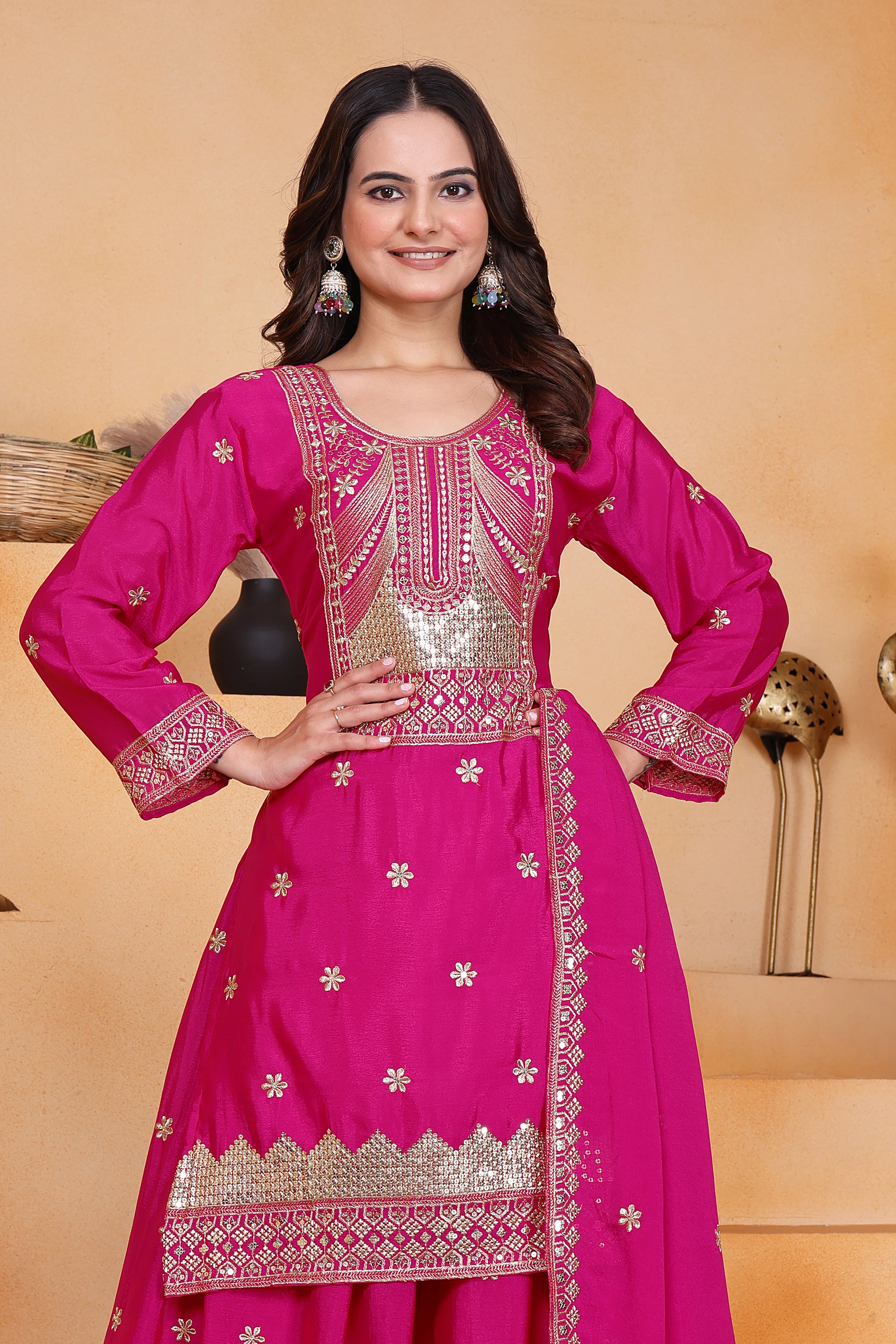 Woman wearing a pink traditional outfit with intricate designs on a beige background
