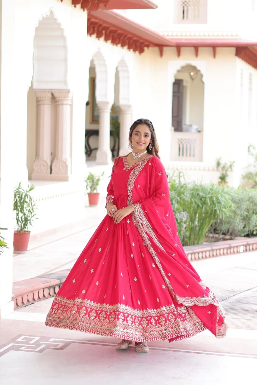 Woman in a pink traditional outfit standing in front of an architectural building.