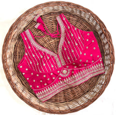 Pink embroidered blouse with gold details on a woven basket