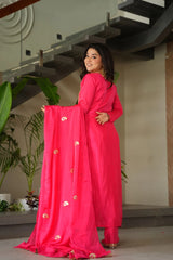 Woman in a bright pink traditional outfit with gold details indoors.