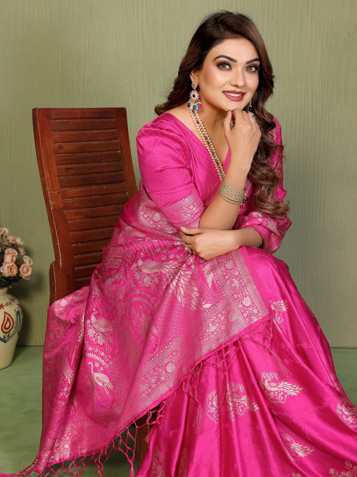 Woman in a bright pink saree with a green background