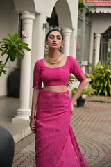 Woman in a pink traditional outfit standing outdoors with columns and plants in the background