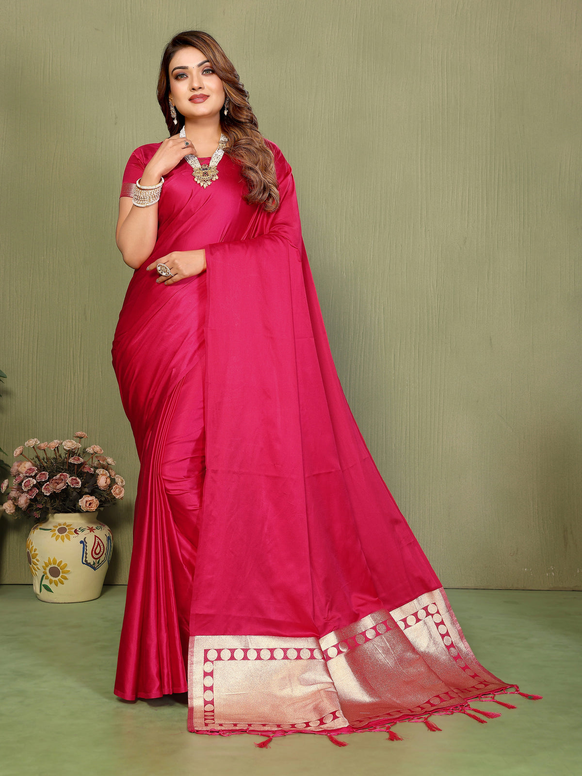 Woman wearing a bright pink saree with a green background
