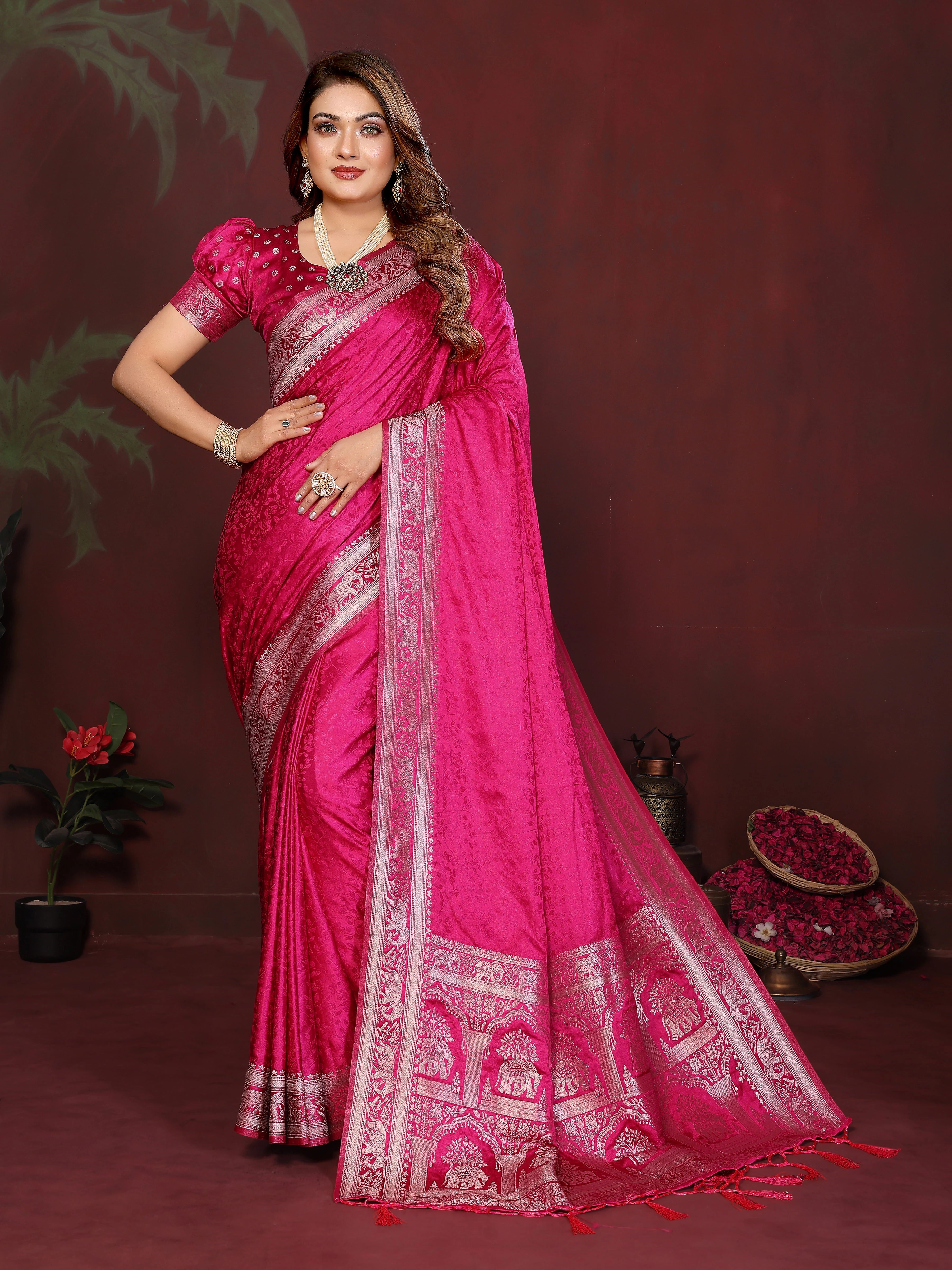 Woman wearing a pink saree with intricate designs on a dark background