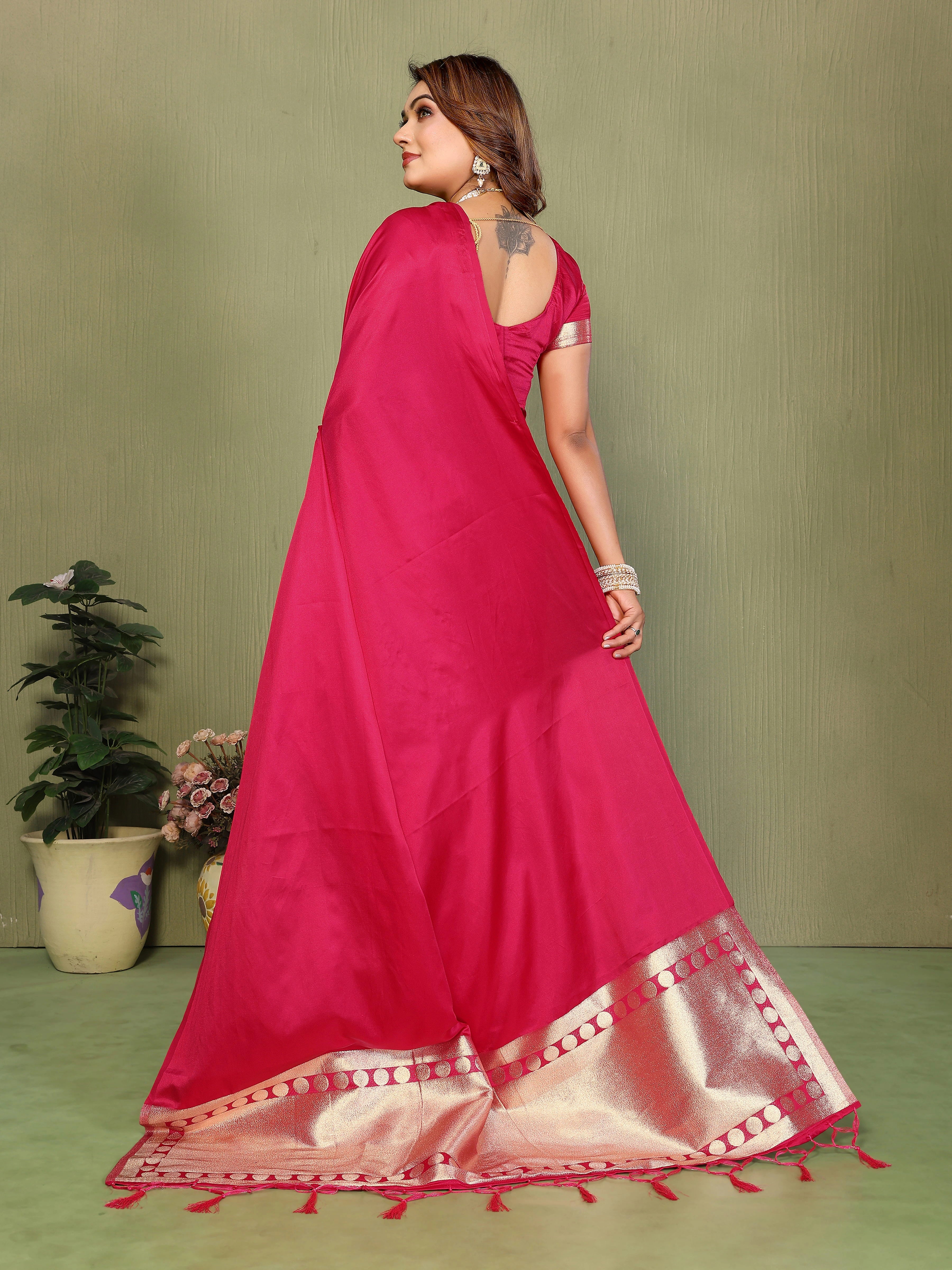Woman wearing a pink saree with a gold border against a green background