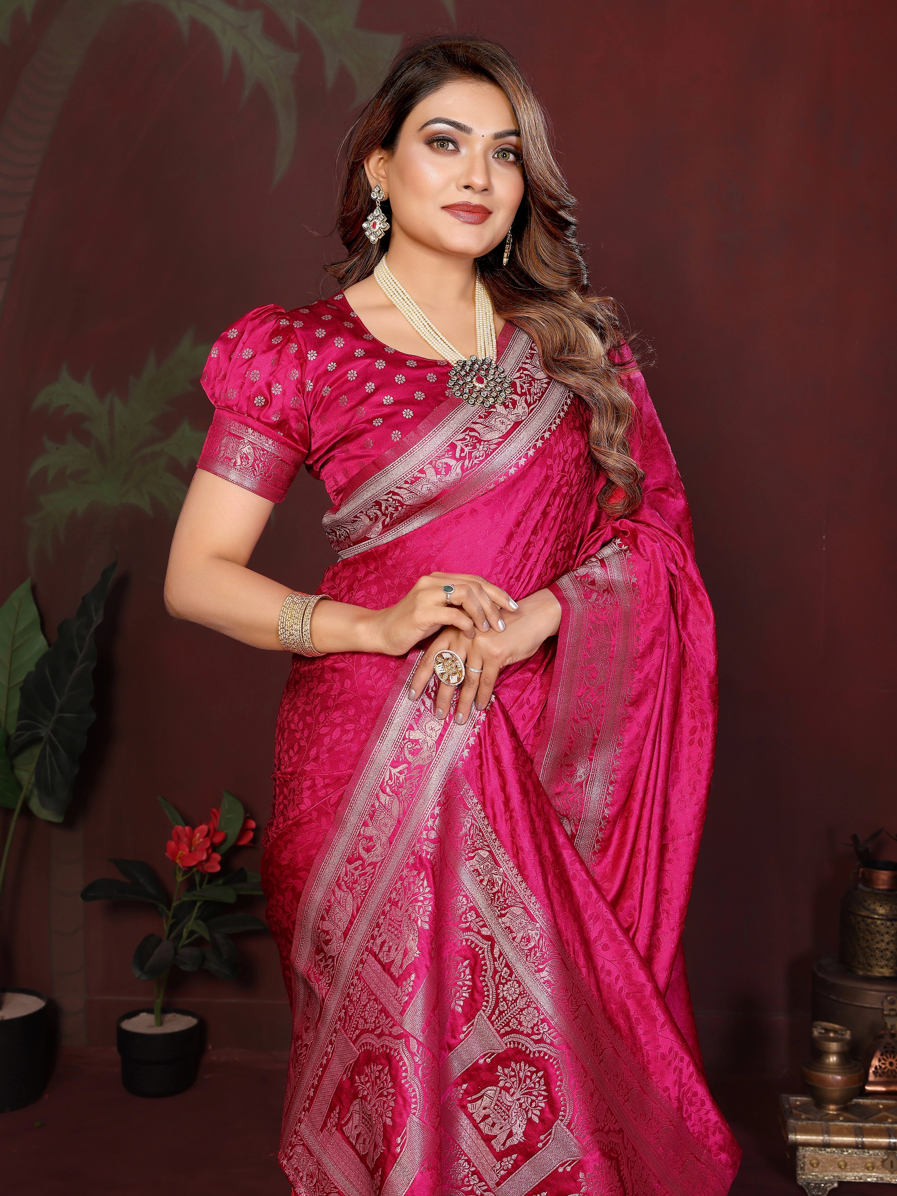 Woman in a pink saree with white patterns against a dark background