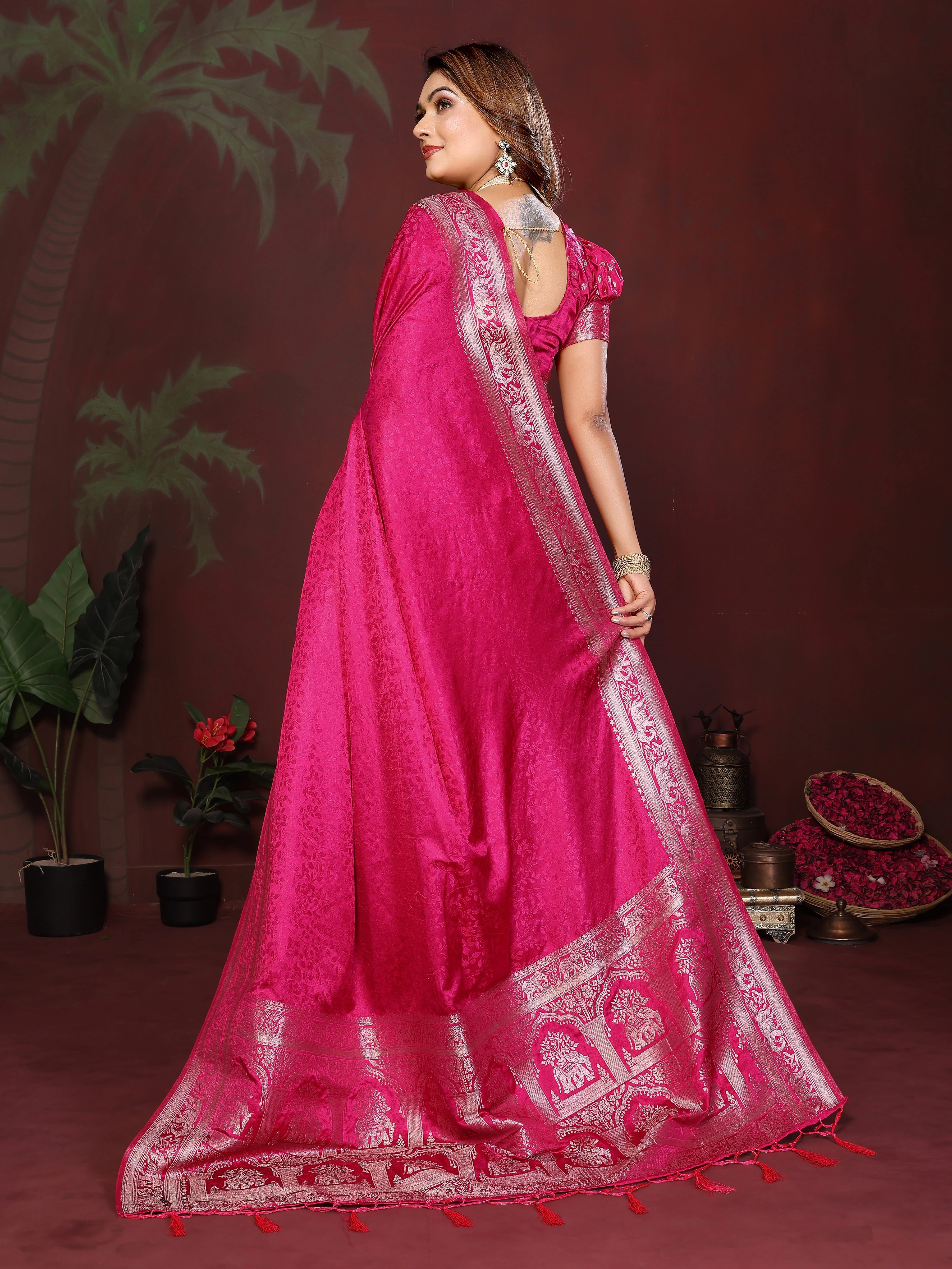 Woman wearing a bright pink saree with white embroidery against a dark background