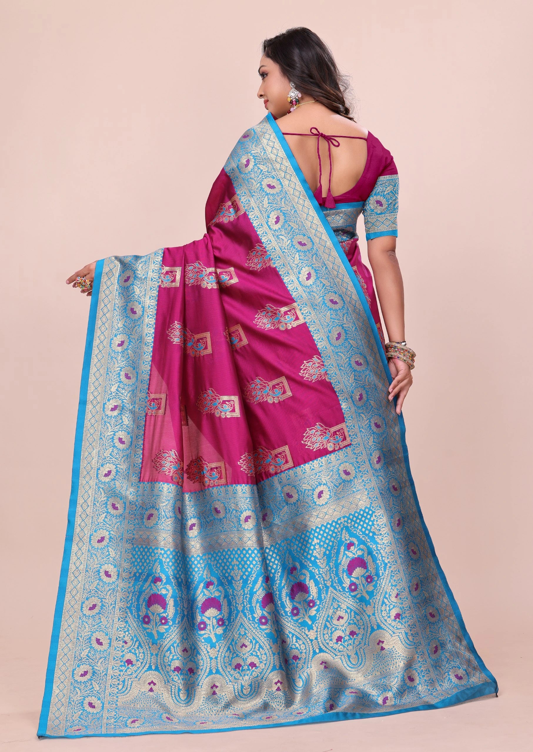 Woman wearing a pink and blue saree with a pattern on a beige background