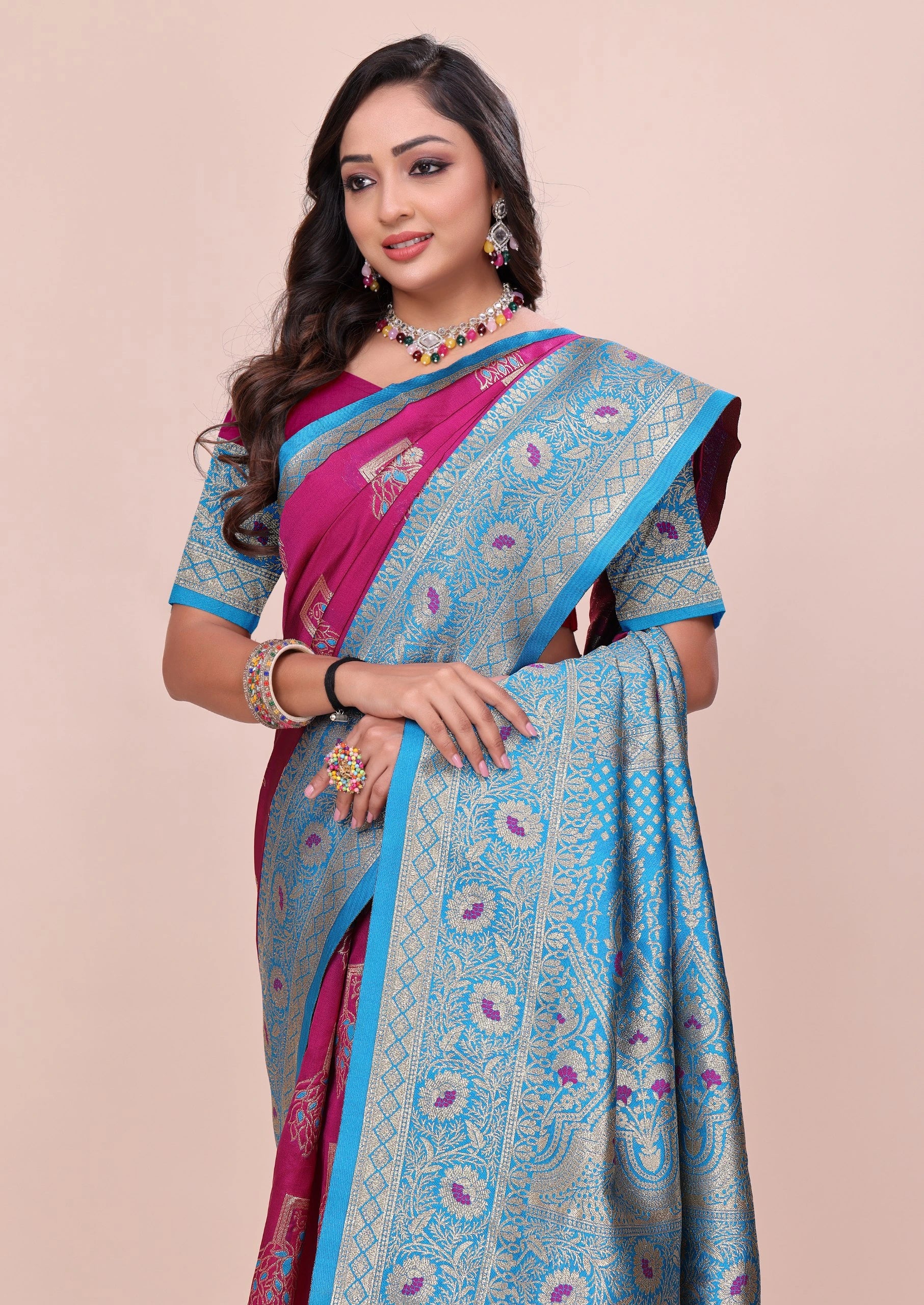 Woman wearing a blue and pink saree with a beige background