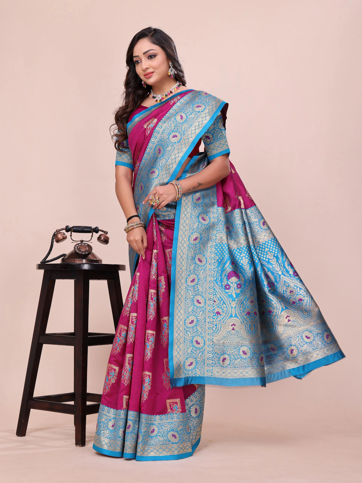 Woman wearing a traditional saree with a pink and blue design on a beige background