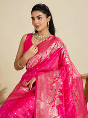 Woman wearing a bright pink saree with gold patterns on a beige background