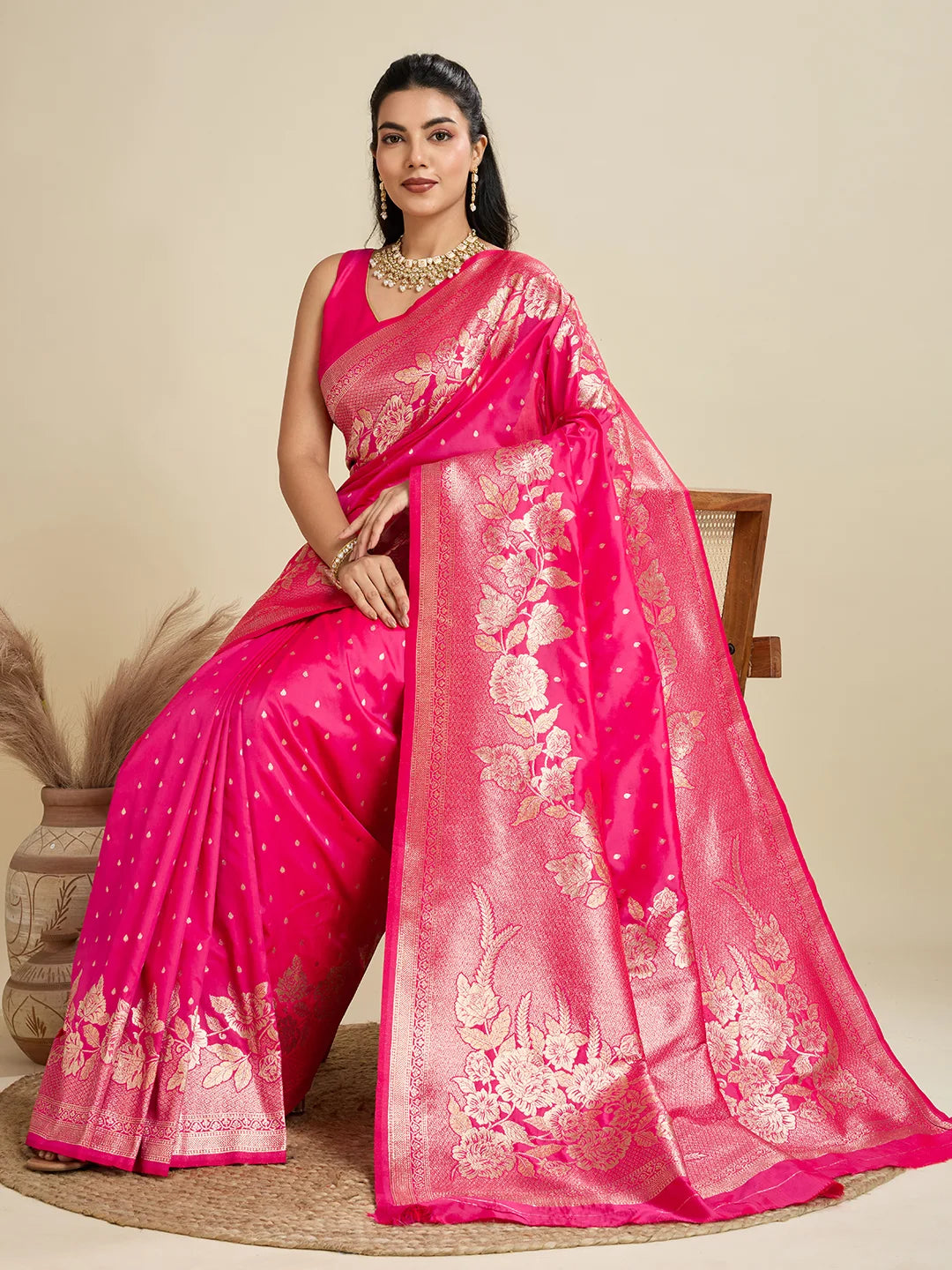 Woman wearing a pink saree with floral patterns on a beige background