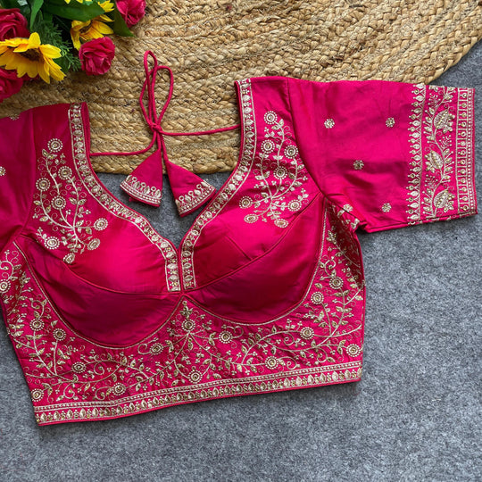 Pink embroidered blouse on a textured surface with flowers in the background