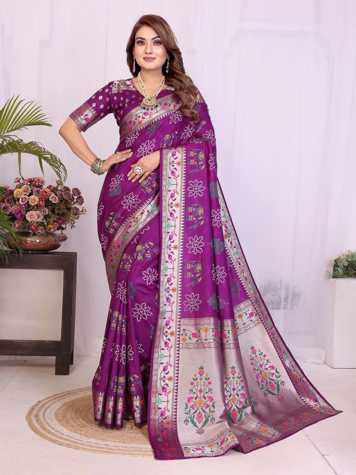 Woman wearing a purple saree with floral patterns indoors.