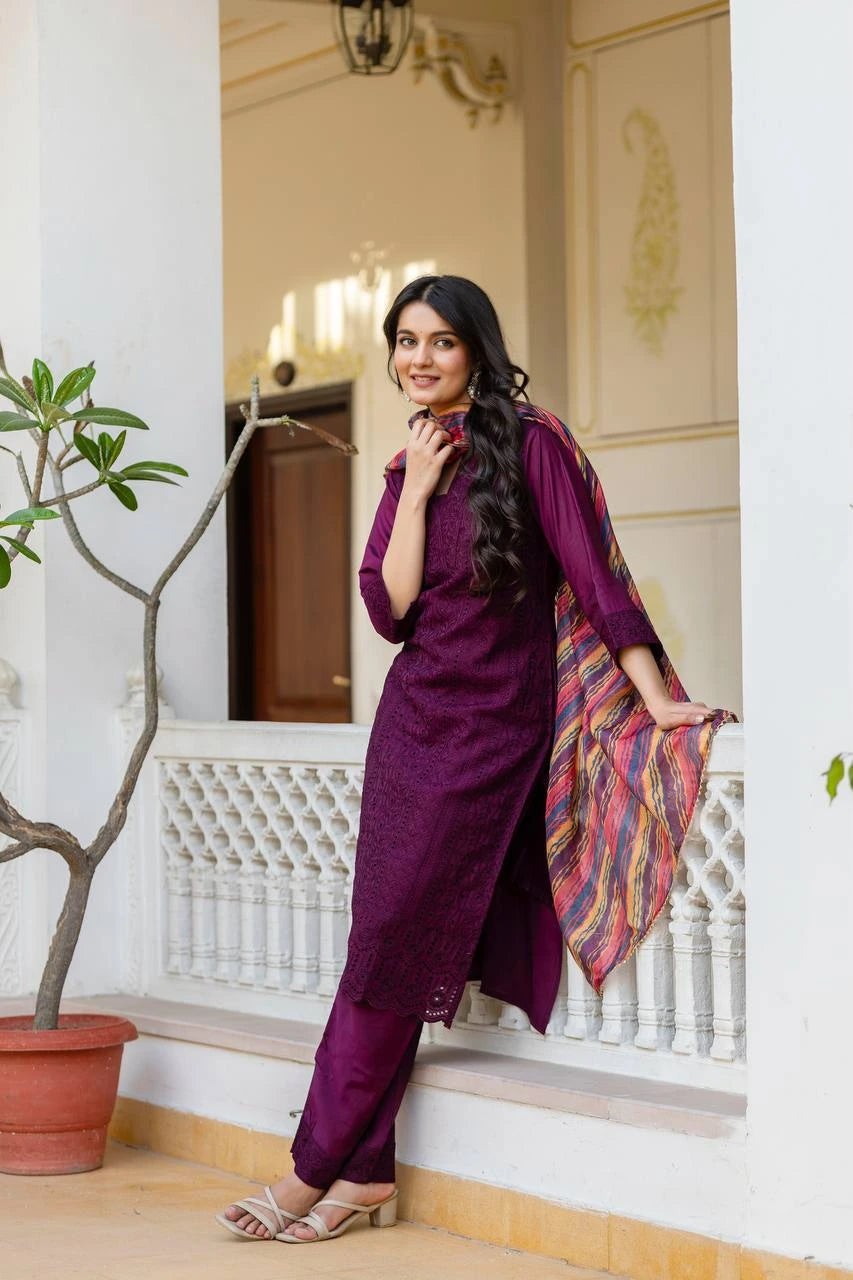 Woman in a purple traditional outfit standing on a staircase with decorative elements.