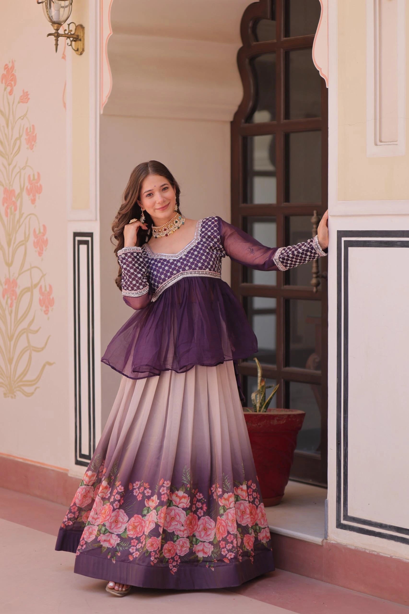 Woman in a purple and floral dress standing in a decorated room.