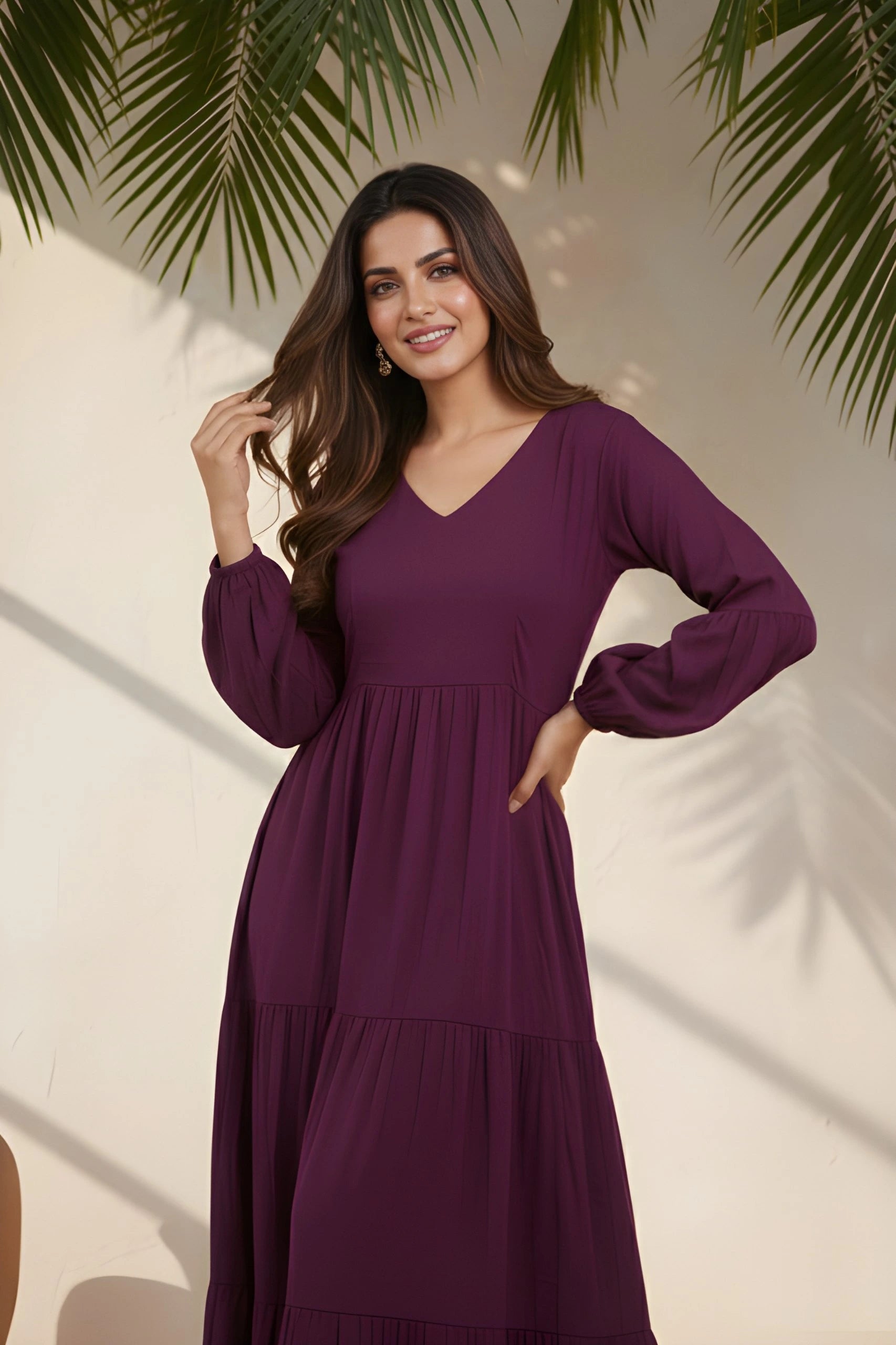 Woman wearing a purple dress standing against a light background with green leaves.