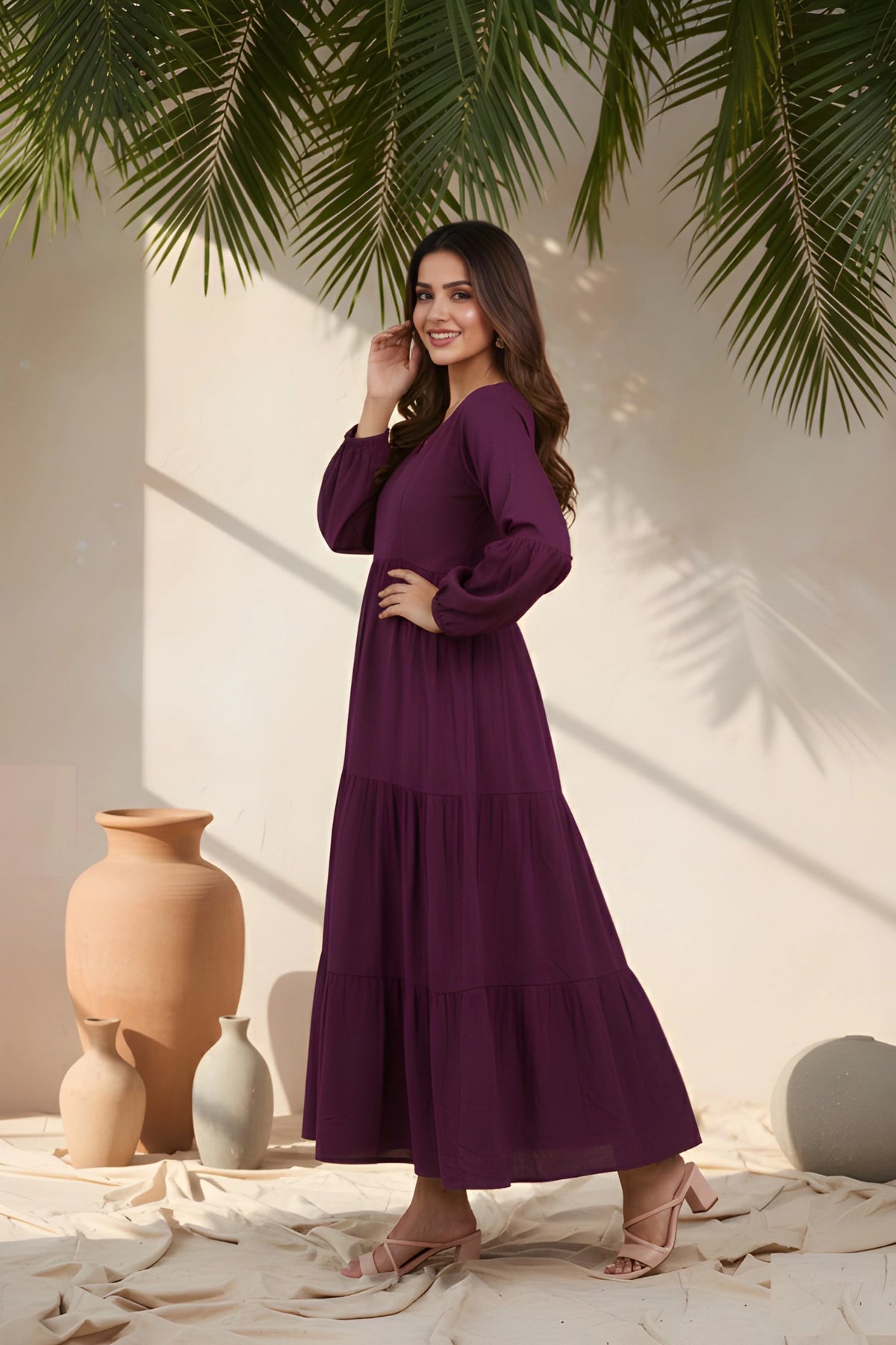 Woman in a purple dress standing in a sunlit room with plants and vases.