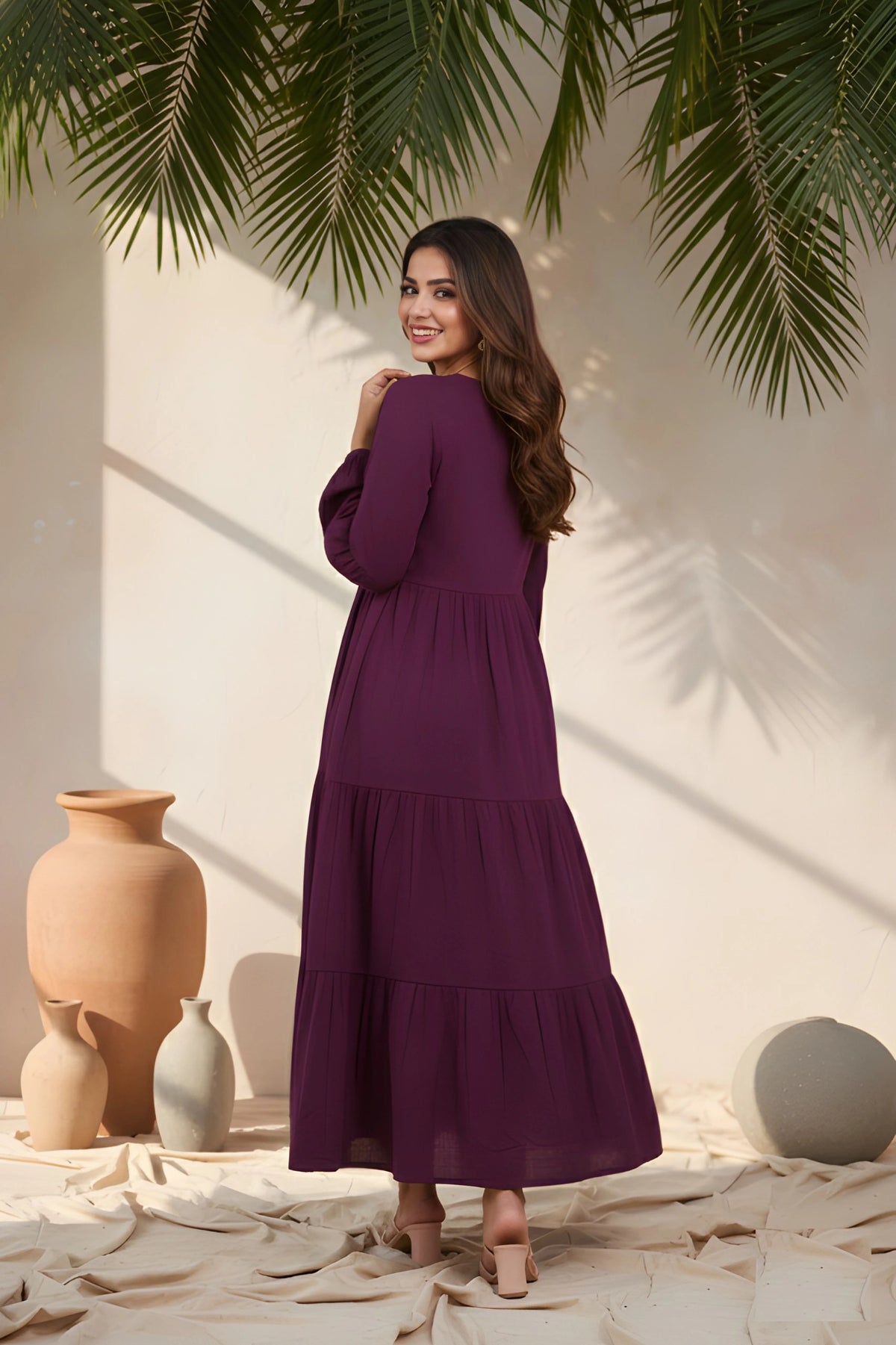 Woman in a purple dress standing in a decorative setting with vases and plants.