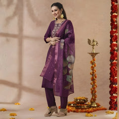 Woman in a purple traditional outfit standing next to decorative elements on a beige background