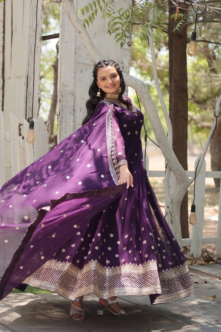 Woman in a purple traditional outfit with a flowing scarf outdoors.