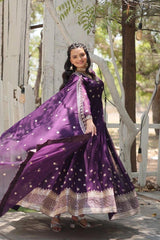 Woman in a purple traditional outfit with a flowing scarf outdoors.