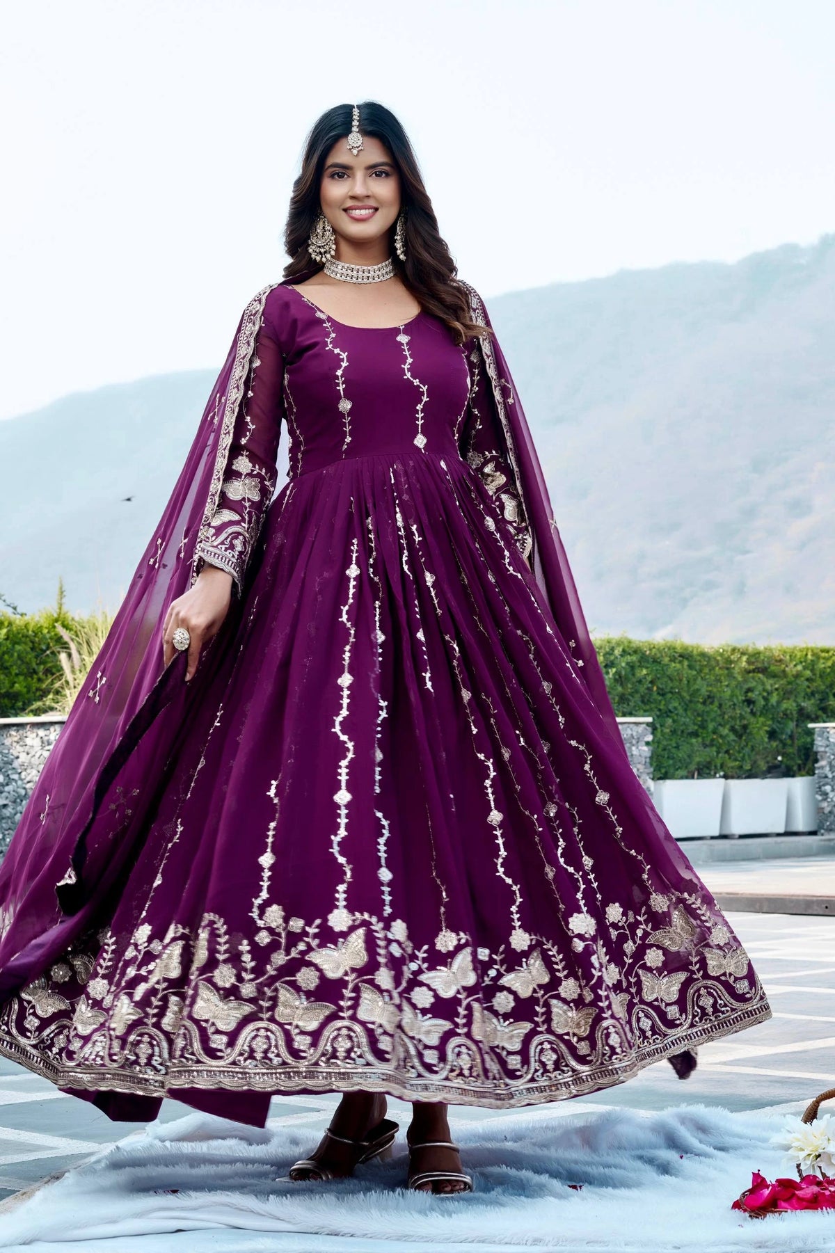 Woman in a purple embroidered dress with a matching dupatta outdoors.