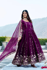 Woman in a purple embroidered traditional outfit standing outdoors with mountains in the background
