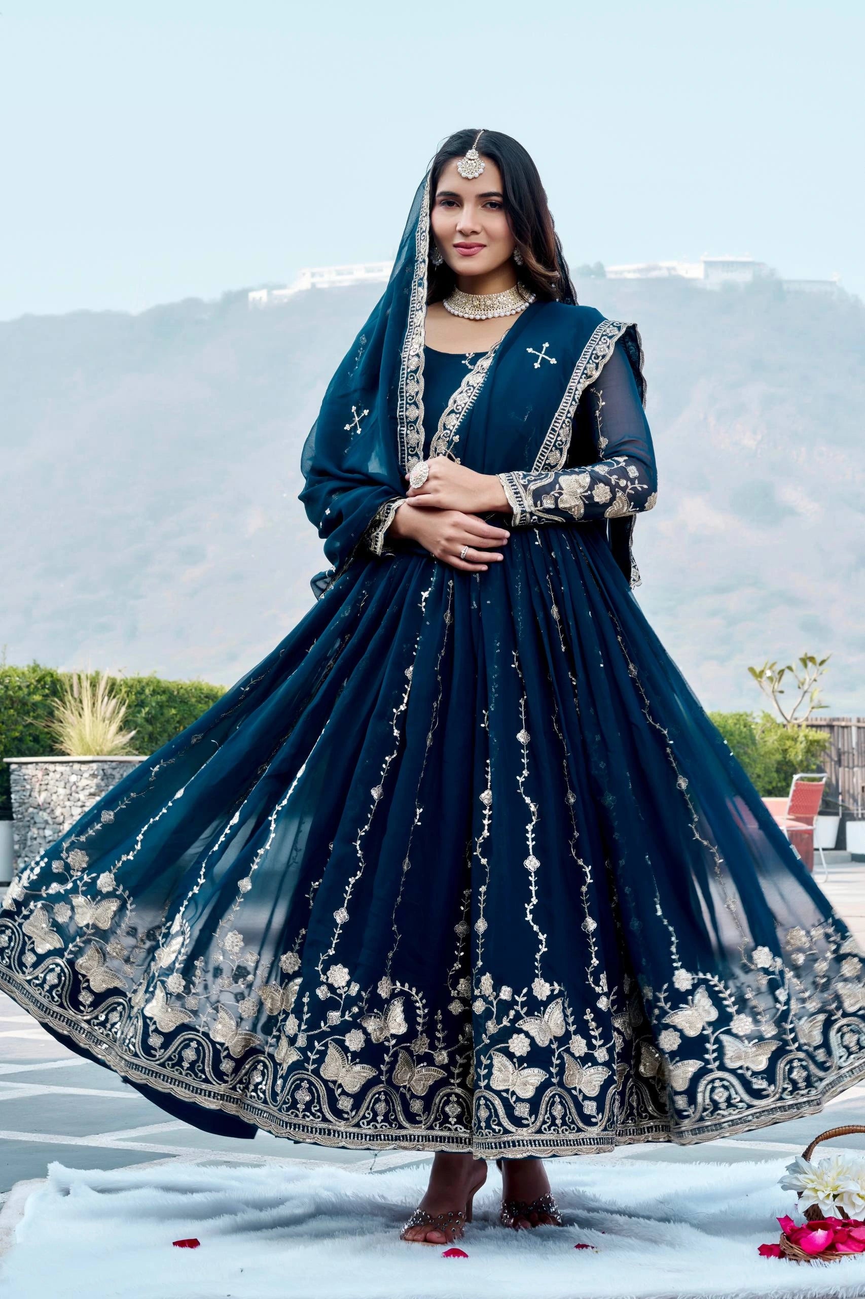 Woman in a traditional blue embroidered outfit with a scenic background