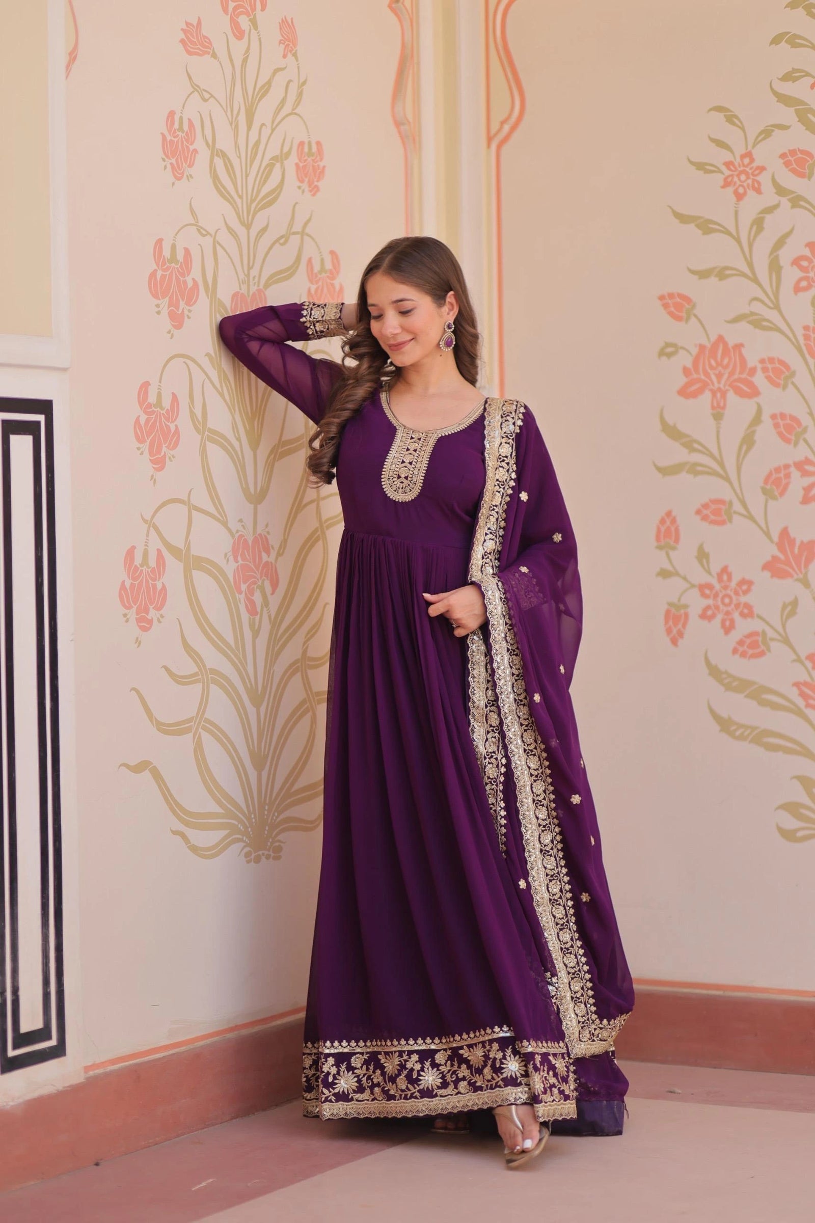 Woman in a purple traditional outfit with floral wall design