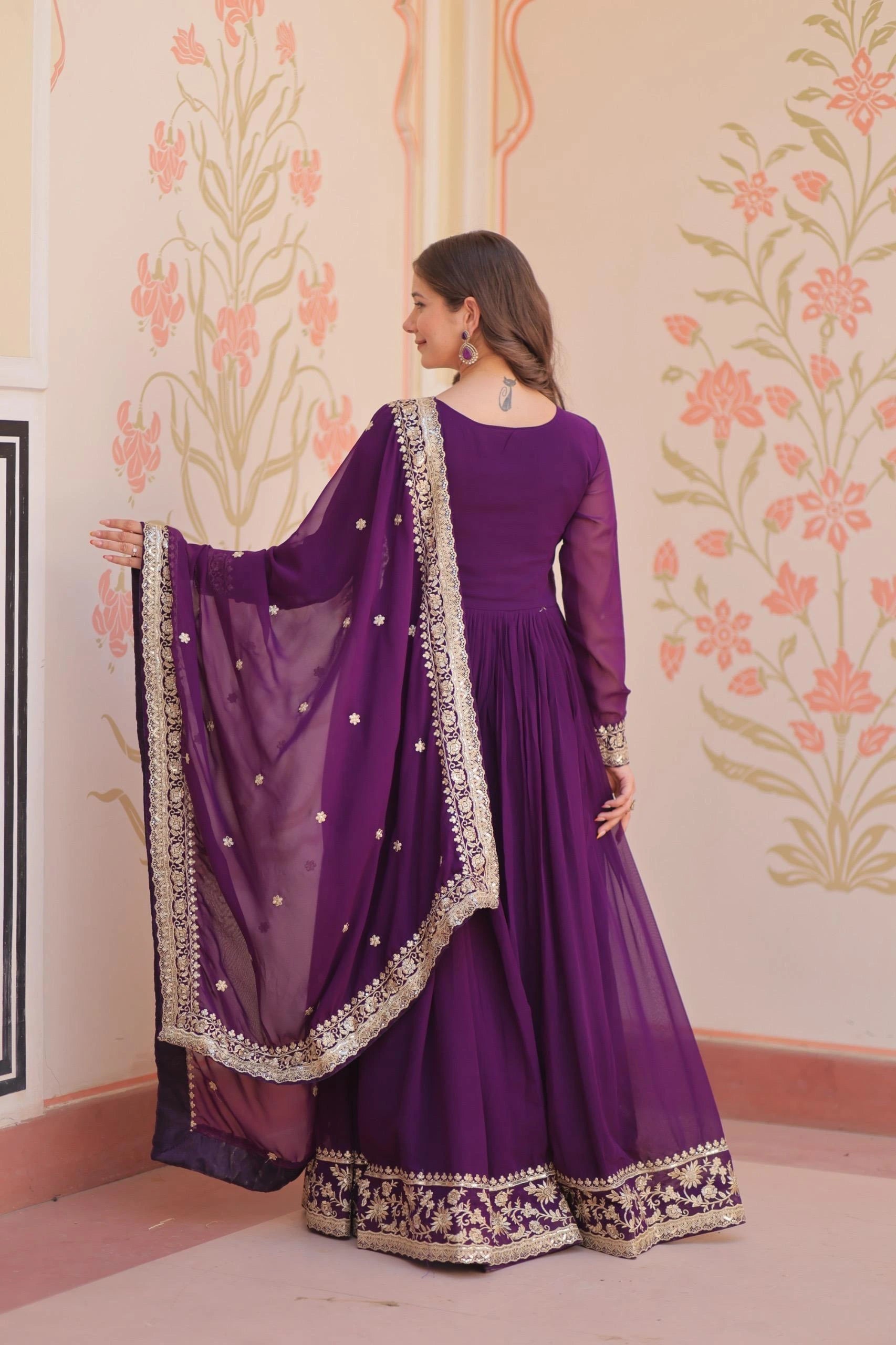 Woman in a purple traditional outfit with a floral wall background