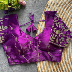 Purple embroidered blouse on a textured surface with flowers in the background